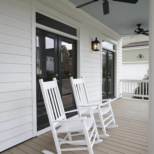 Aerial view of a house with a shingled roof, a backyard patio with outdoor furniture, and surrounded by trees and green lawn.